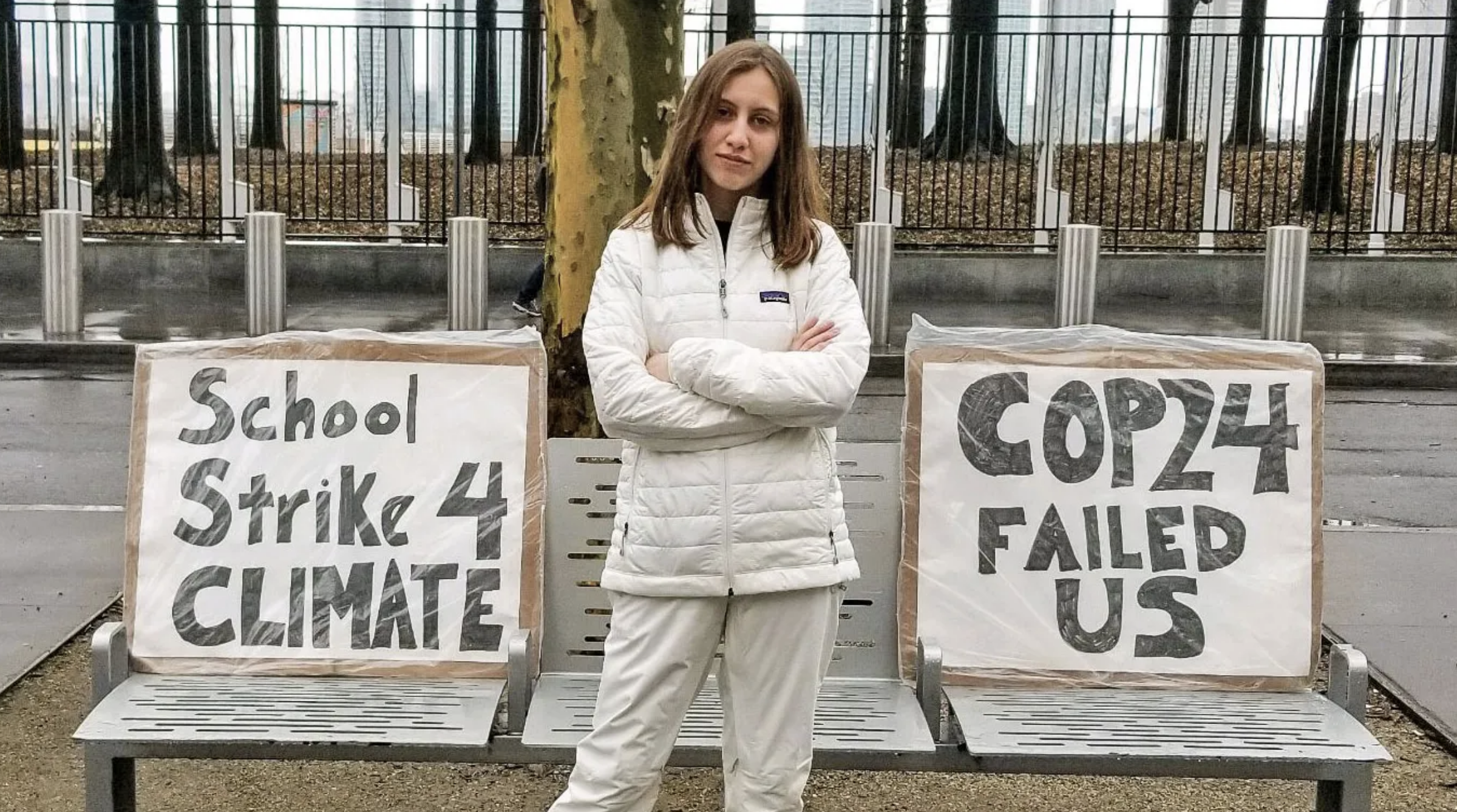 Alexandria Villaseñor standing, arms crossed, in front of signs, including one that reads "school strike 4 climate"