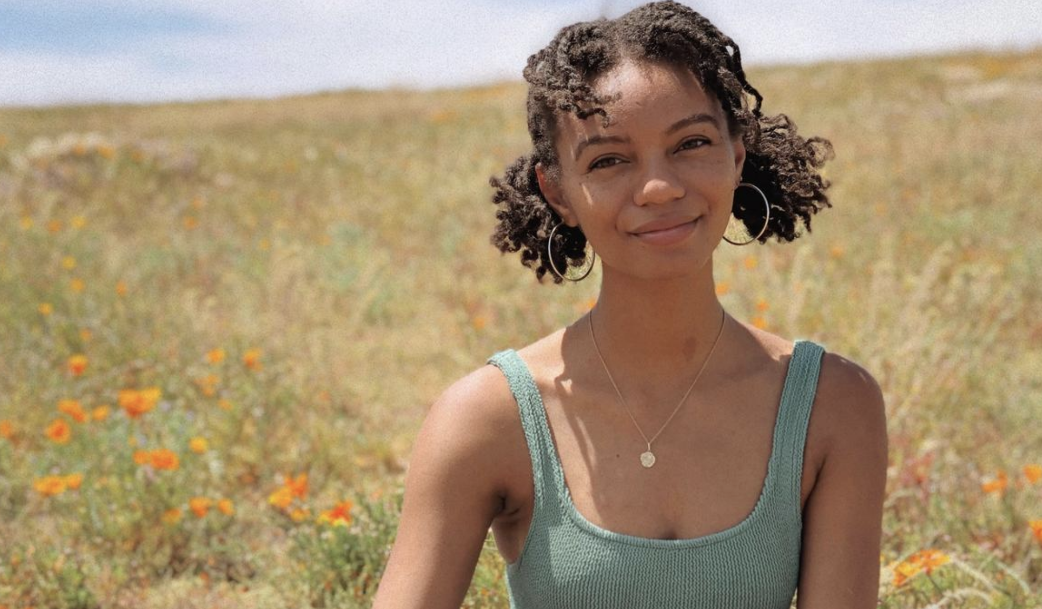 Leah Thomas smiles in front of a field of flowers and grasses