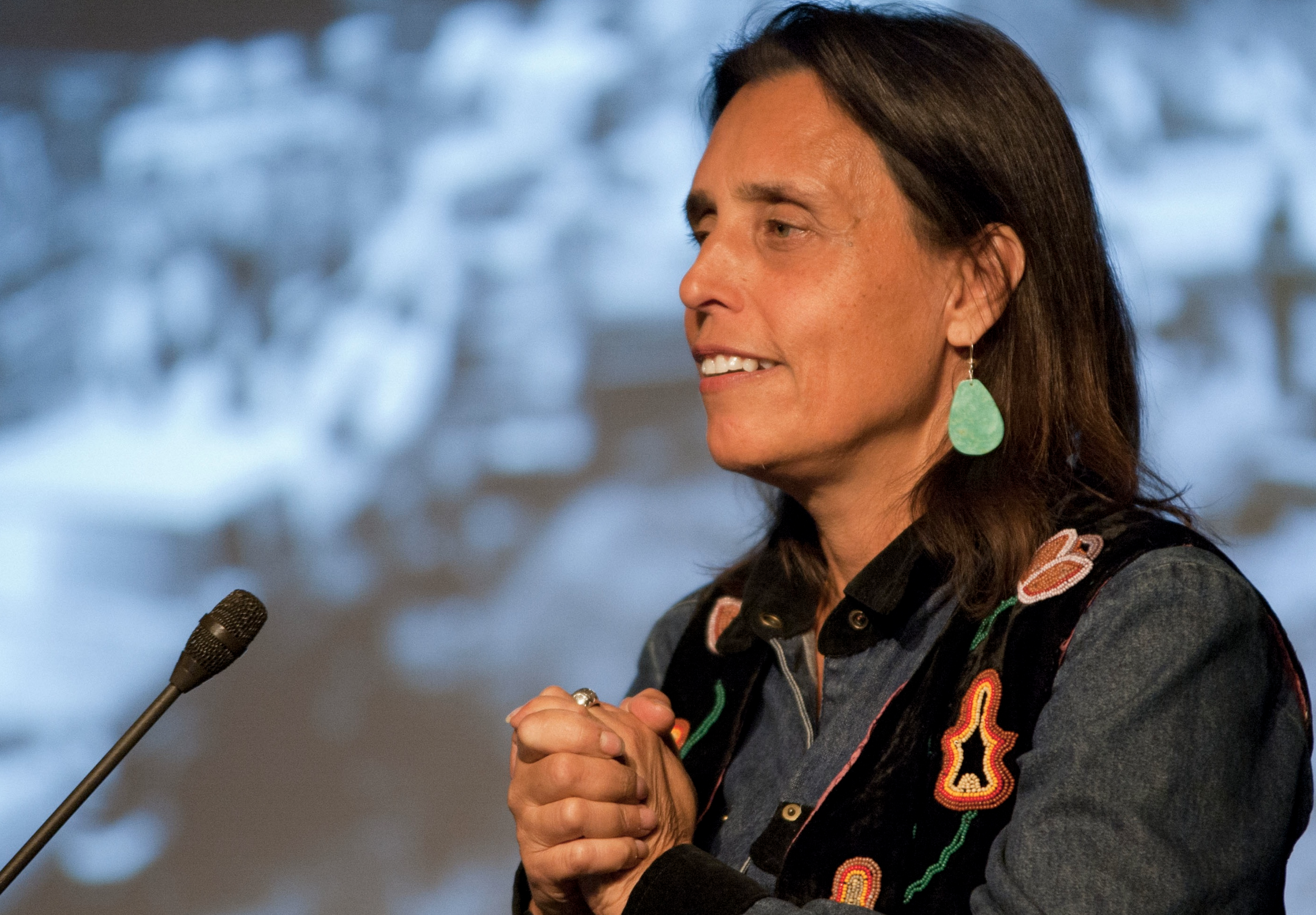 Winona LaDuke smiling on stage in front of a microphone