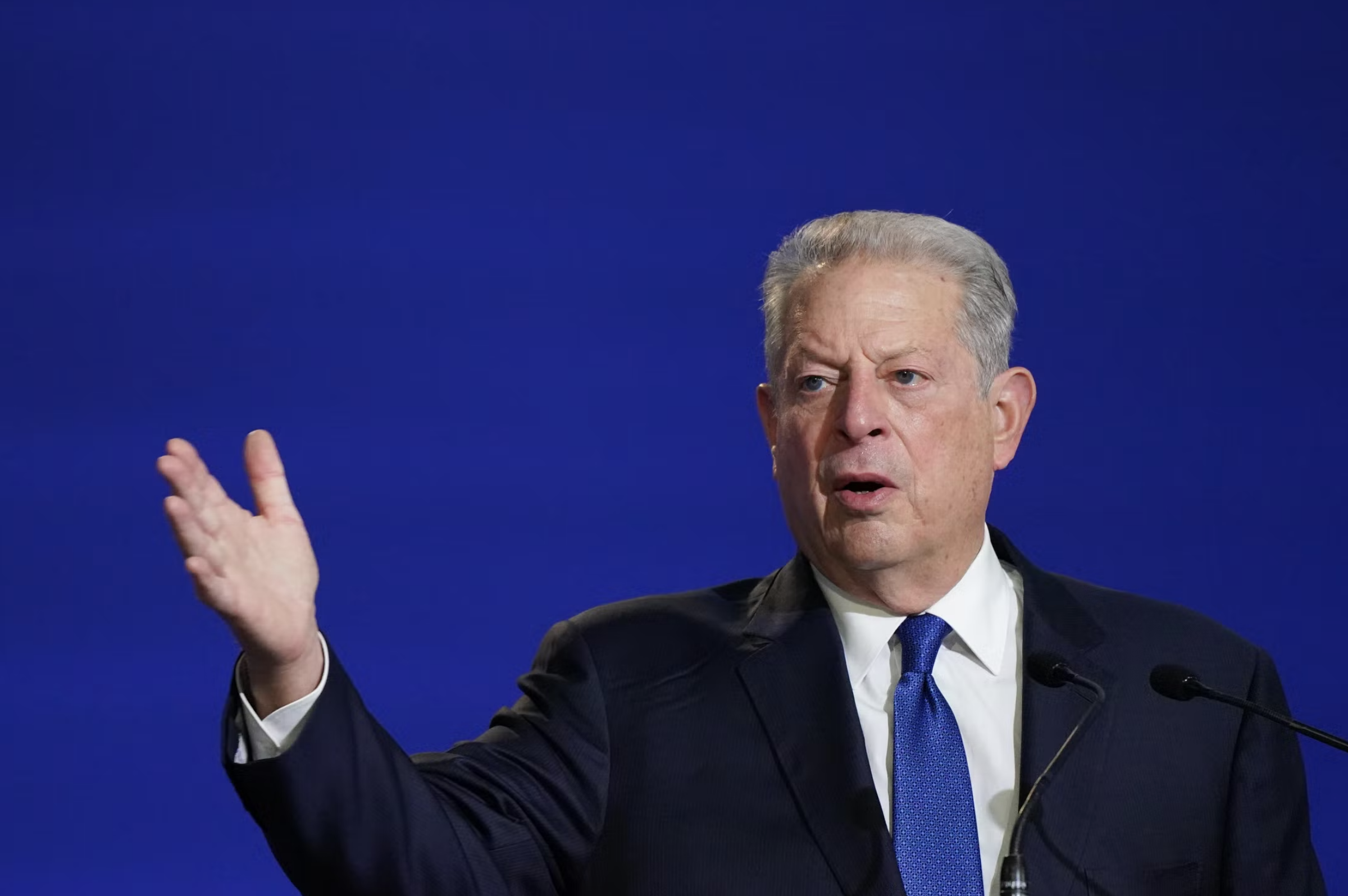 Al Gore giving a speech against a dark blue backdrop