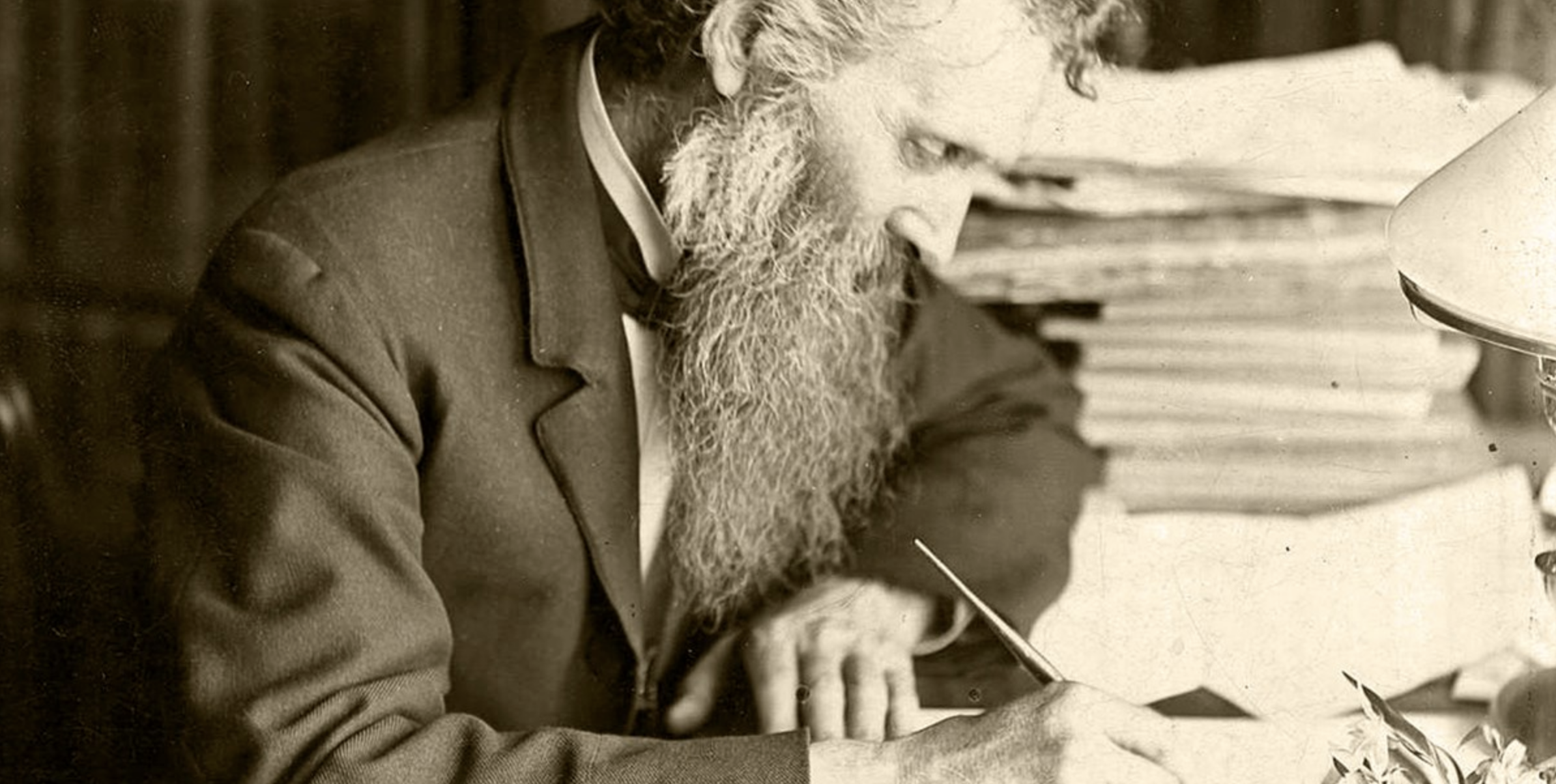 A sepia image of John Muir writing intently