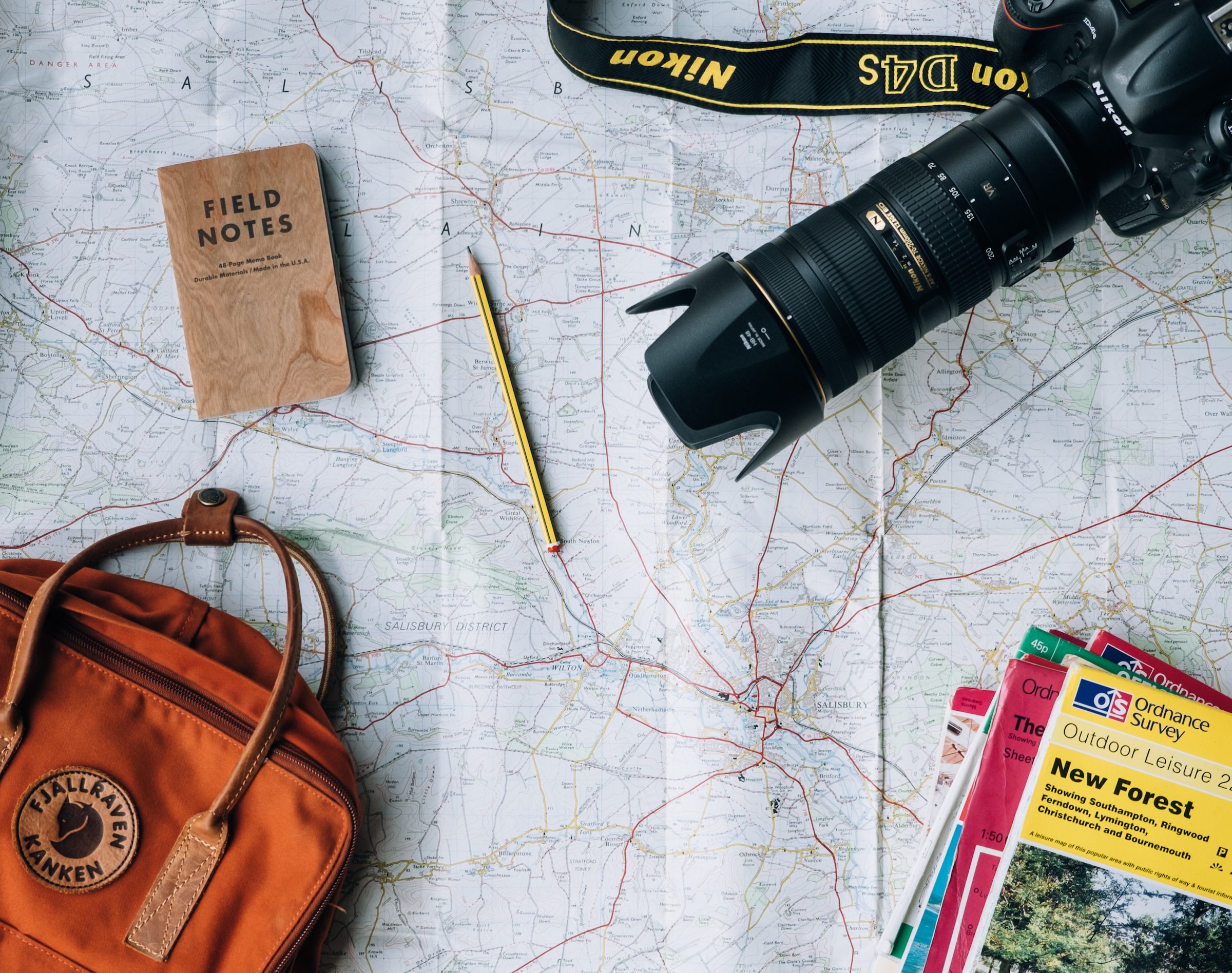 A camera, backpack, and other travel supplies laid out over a map