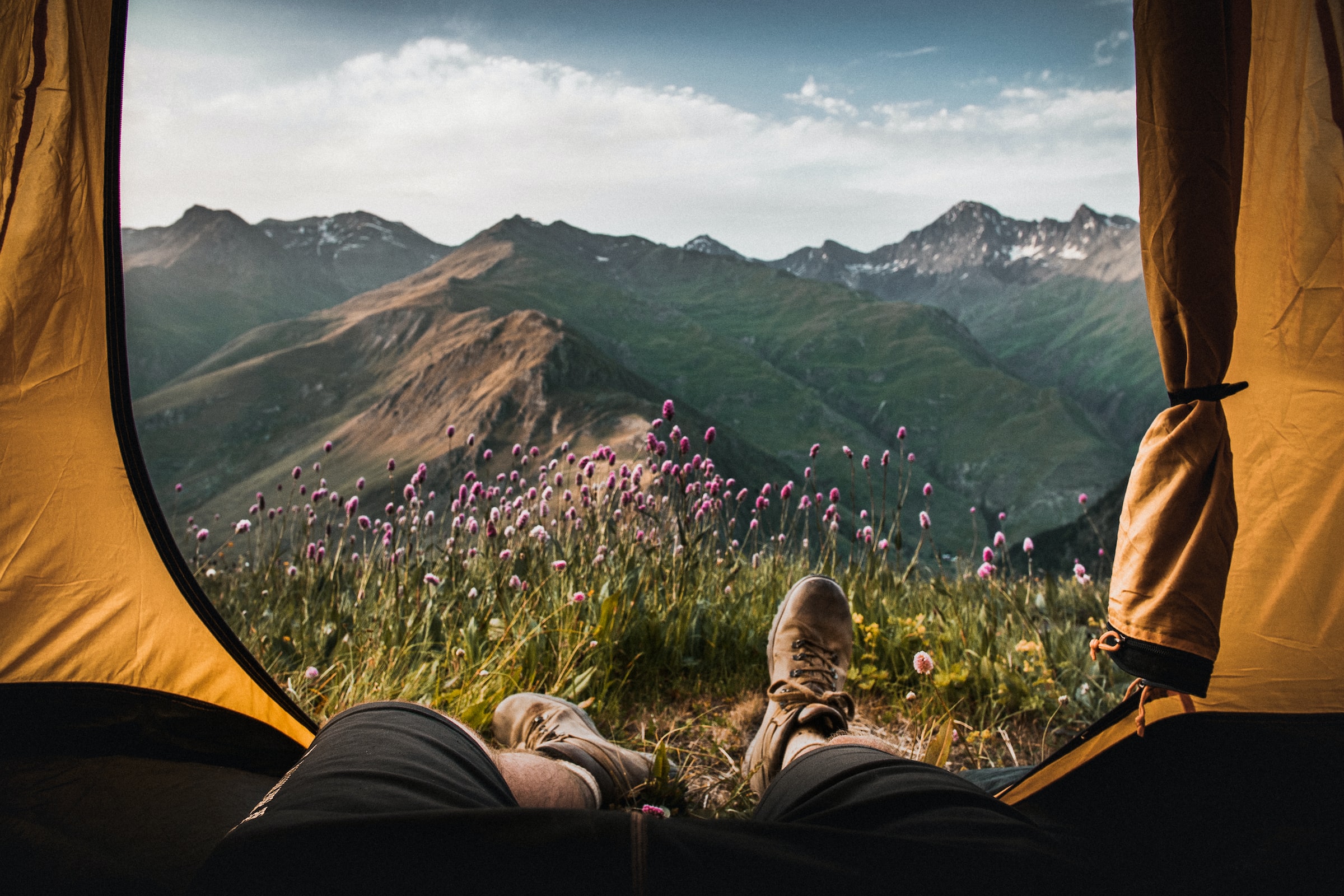 A pair of feet wearing hiking boots are propped up in front of a scenic mountain view