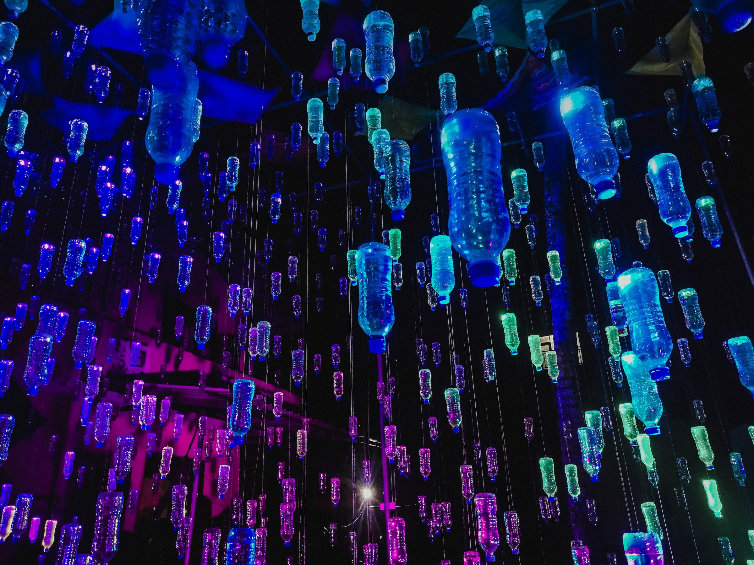 Plastic water bottles hung upside-down in colorful light