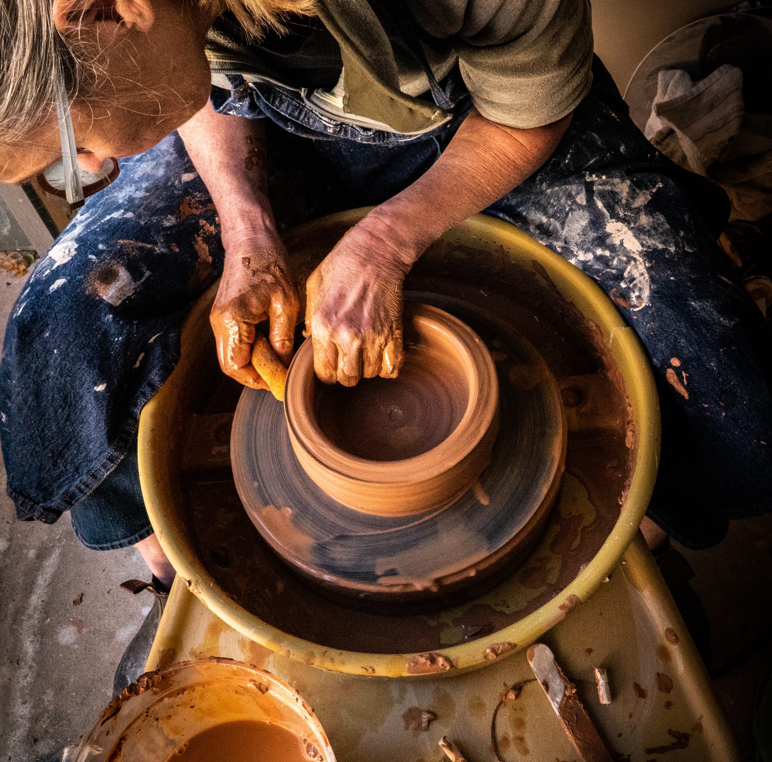 A person uses a pottery wheel to craft a bowl