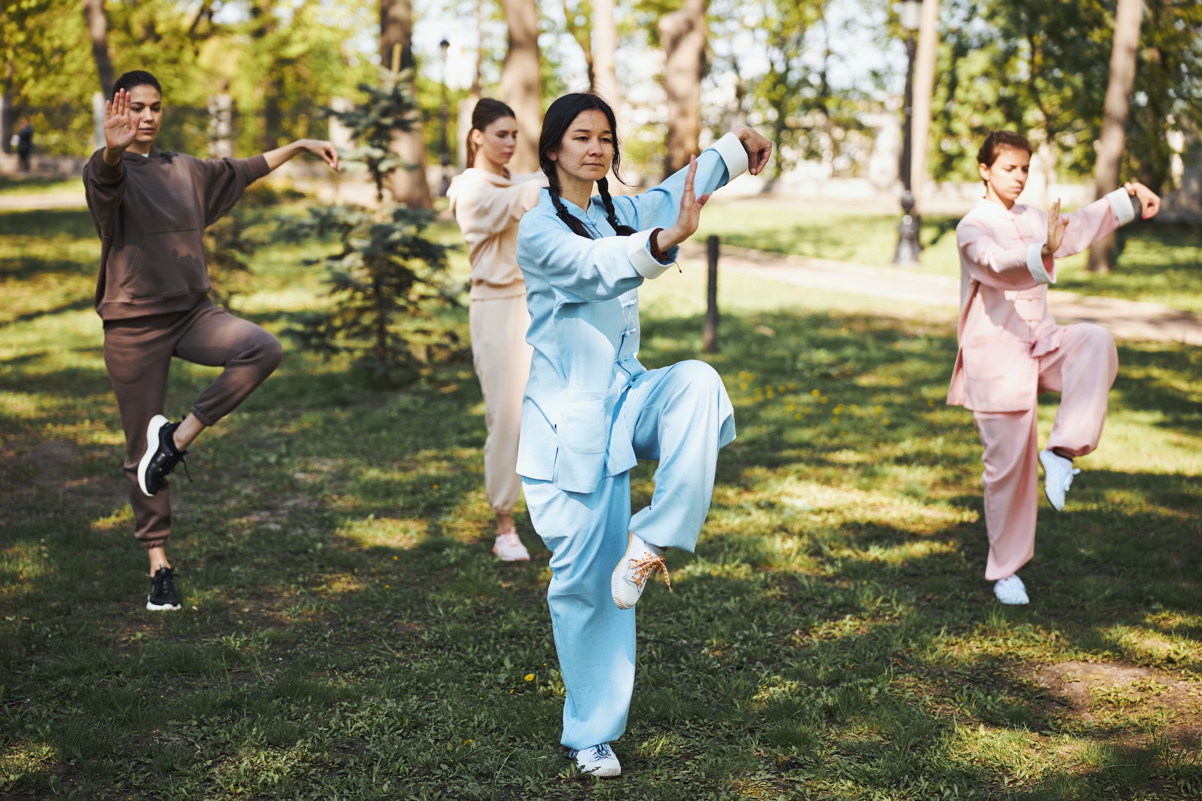 Four people practice Tai Chi in a park