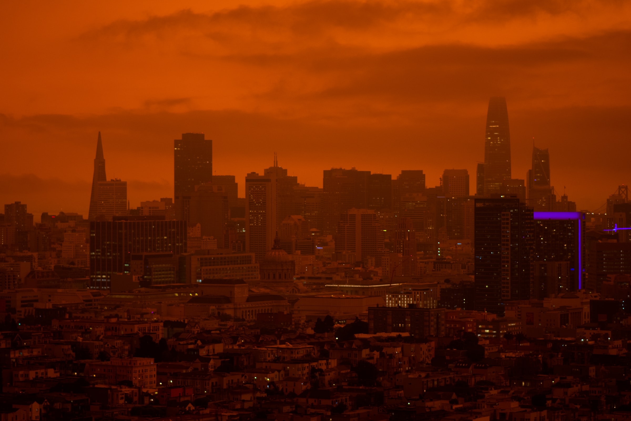A city skyline is obscured by a thick red haze