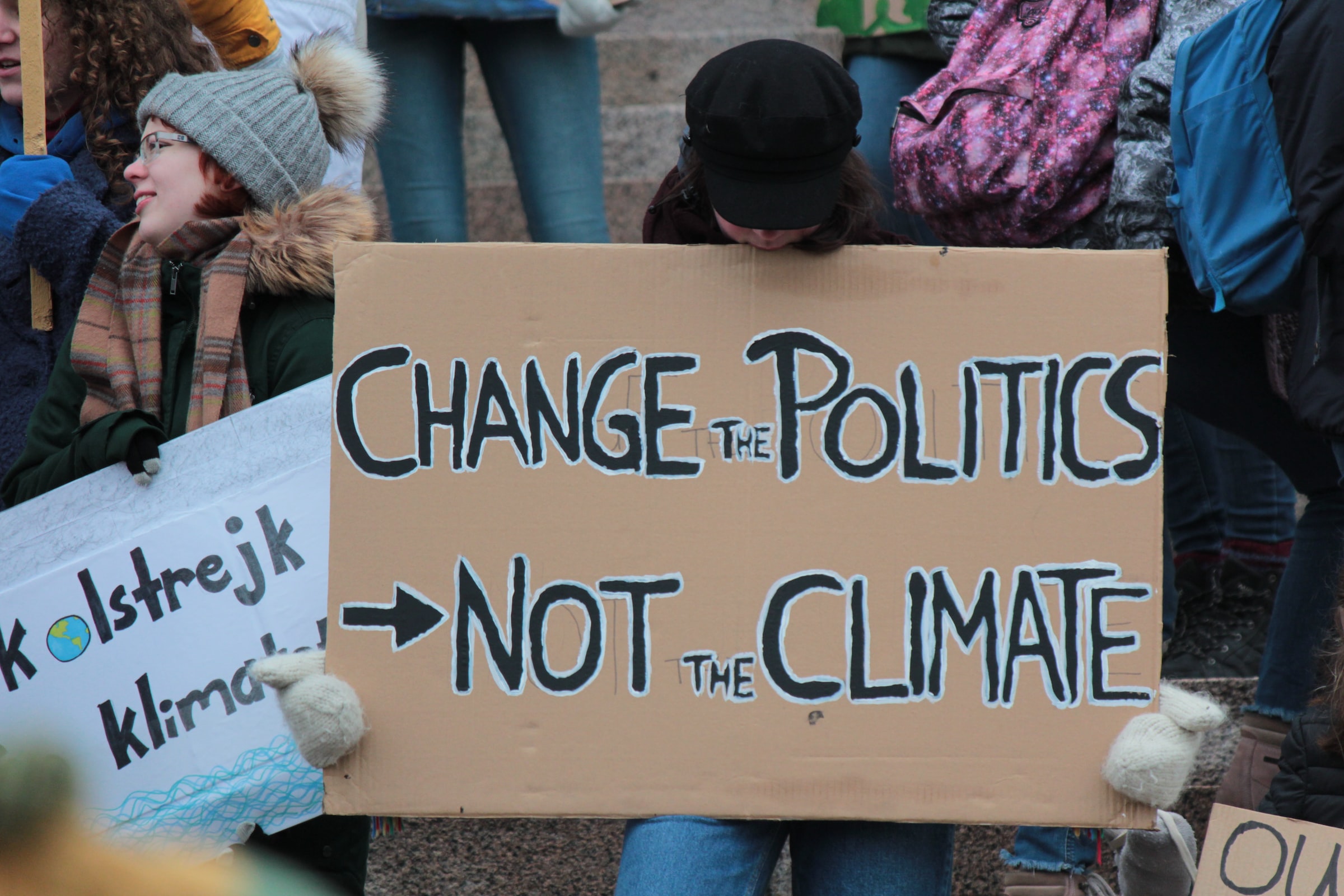 A cardboard sign reads "Change the Politics, Not the Climate"