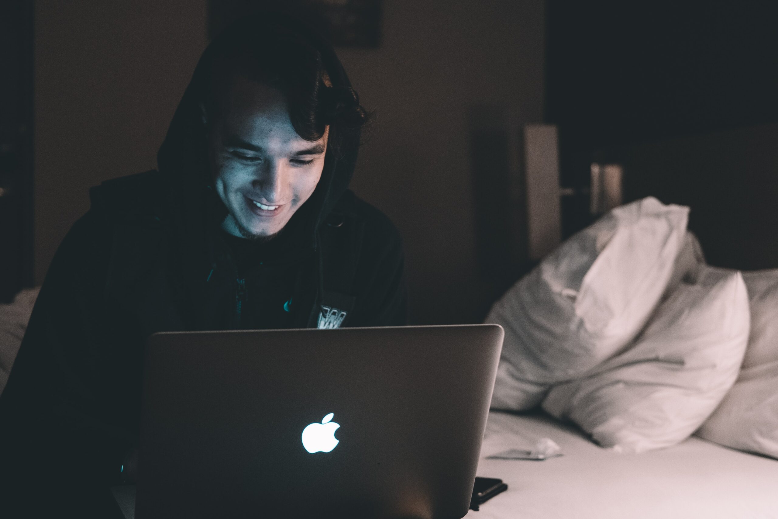 A young person uses their laptop in bed