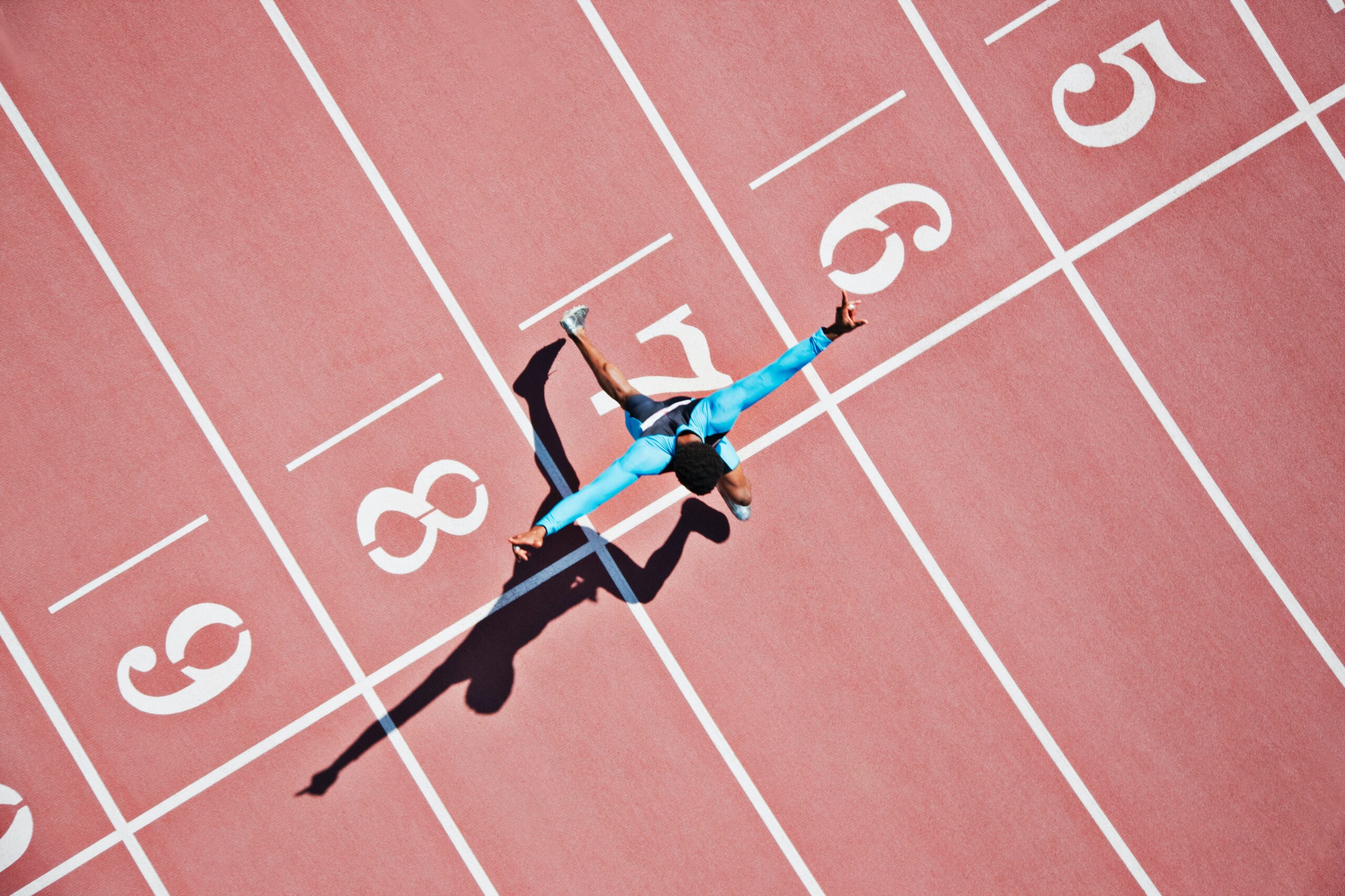 Person crossing a finish line as seen from above.